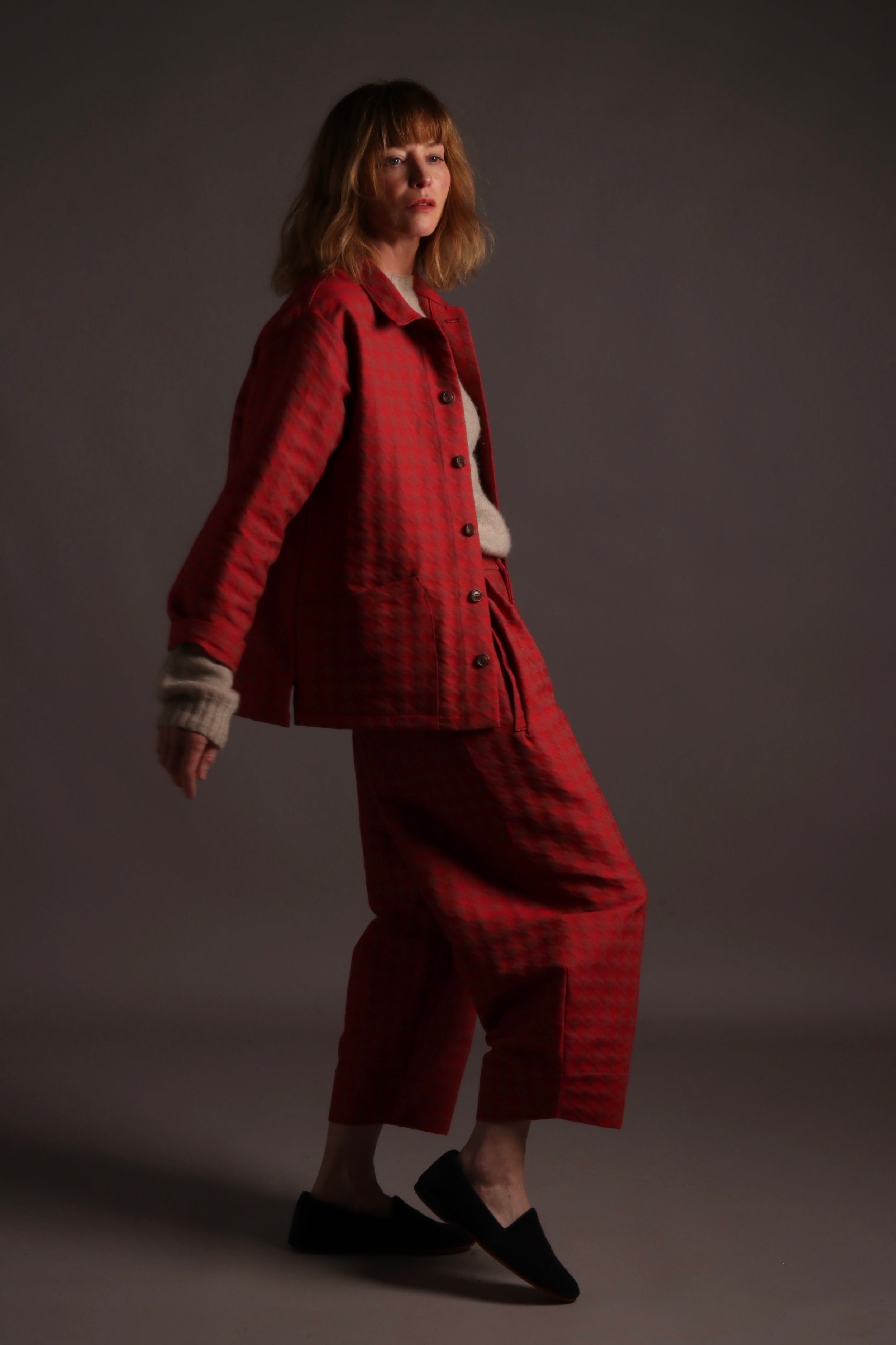 SIENNA WEARS COMFORTABLE BALLOON SHAPED RED HOUNDSTOOTH TROPUSERS AND MATCHING SIMPLE JACKET WITH FIVE BUTTONS AND PATCH POCKETS.