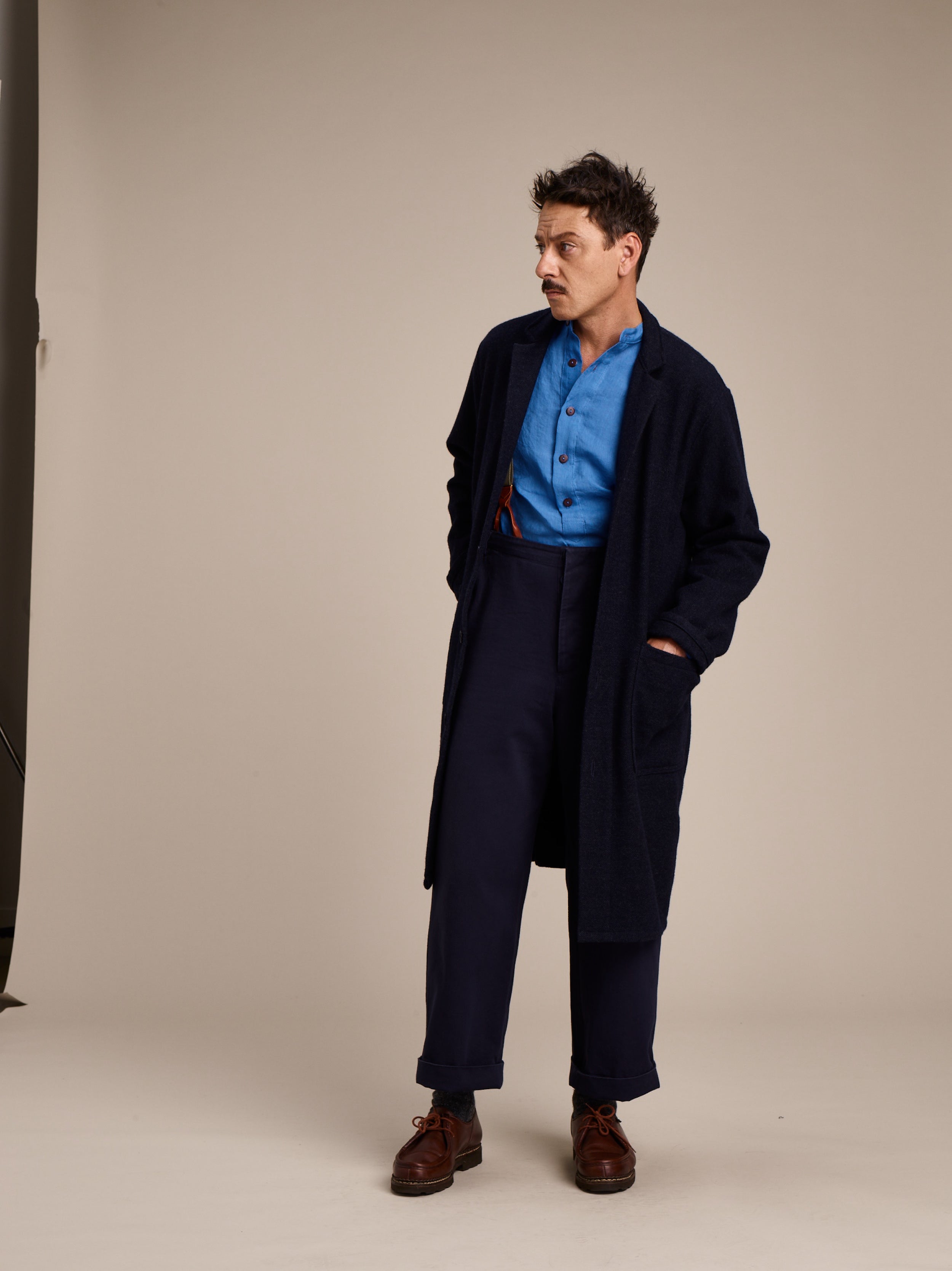 Man wearing Carrier Company Wool Coat in Navy with Linen Collarless Shirt